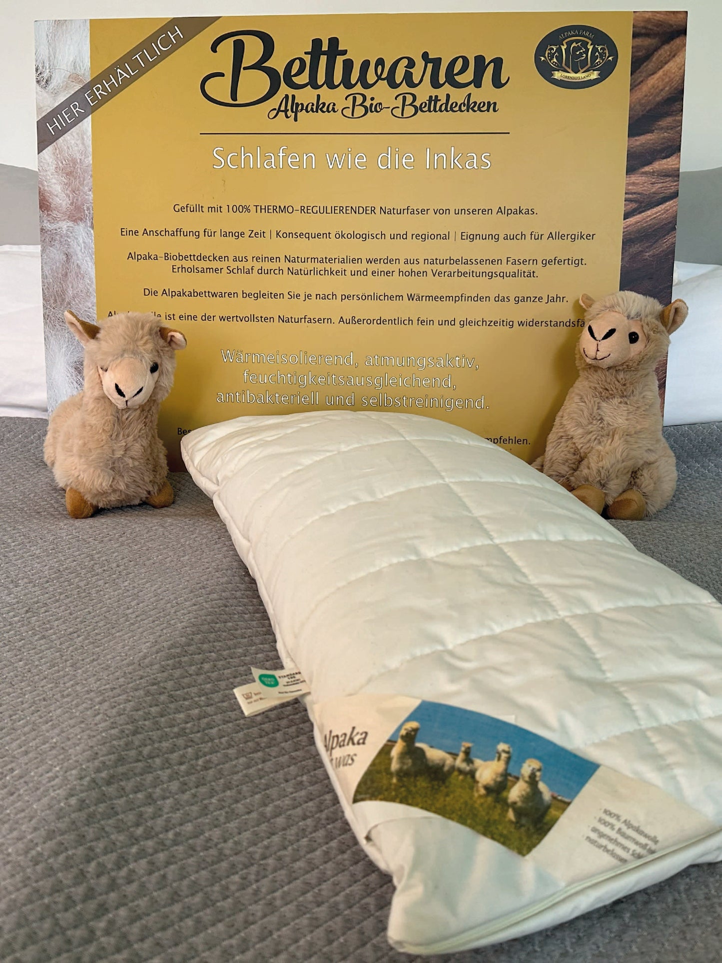 Weißes Alpaka Kissen auf grauer Decke