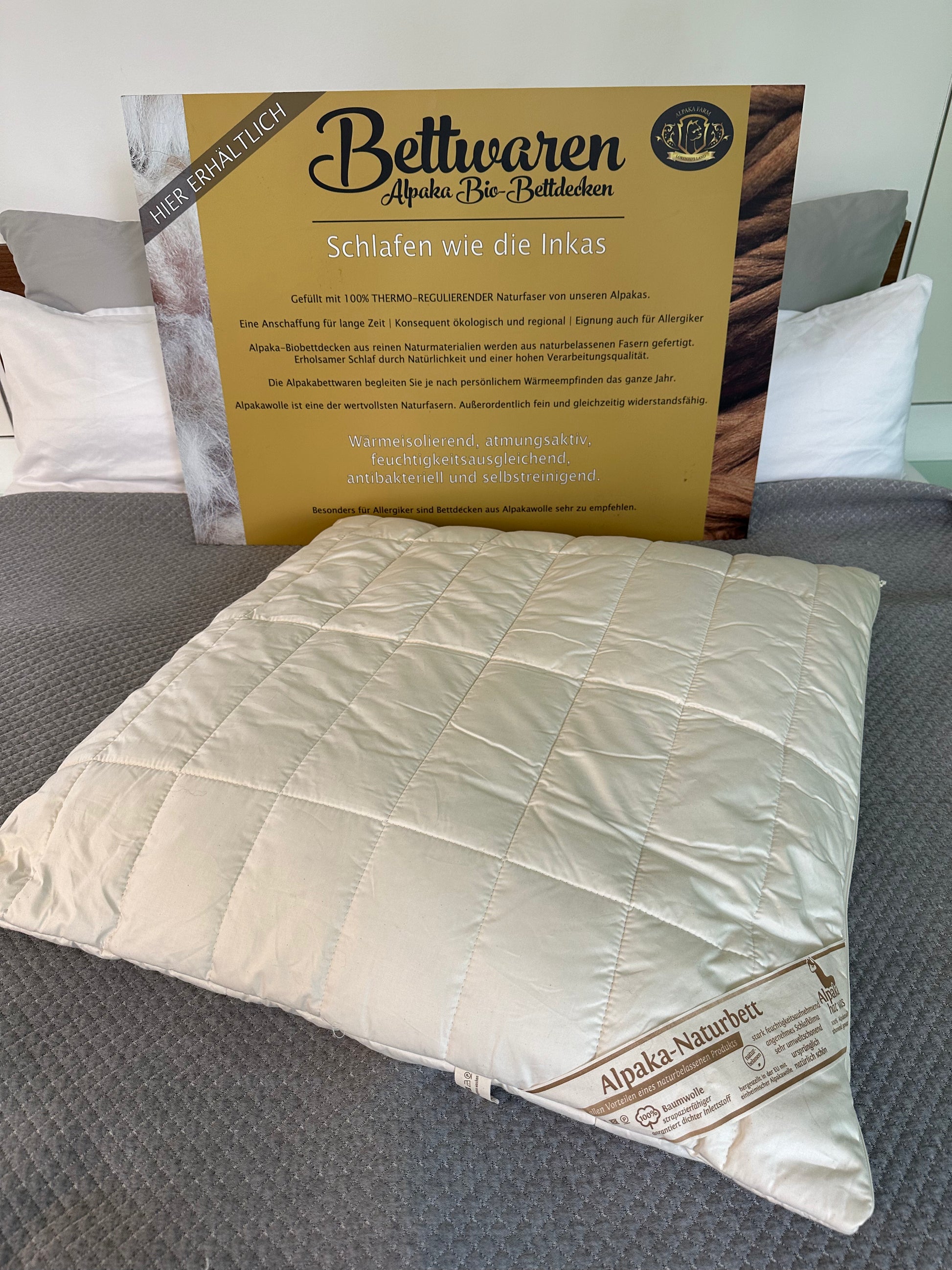 Weißes Alpaka Kissen auf grauer Decke
