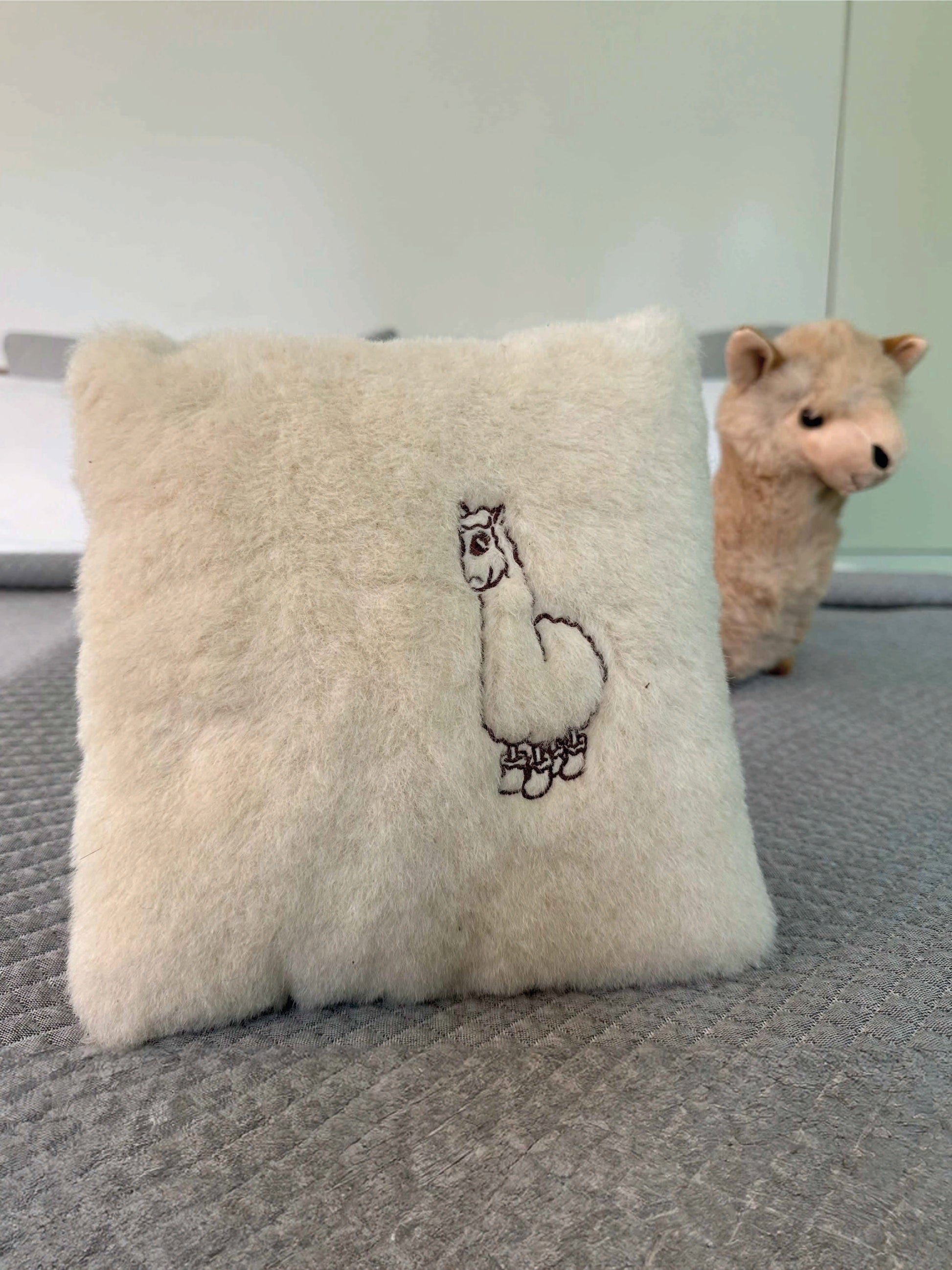 Weißes Kuschelkissen mit einem aufgestickten Alpaka