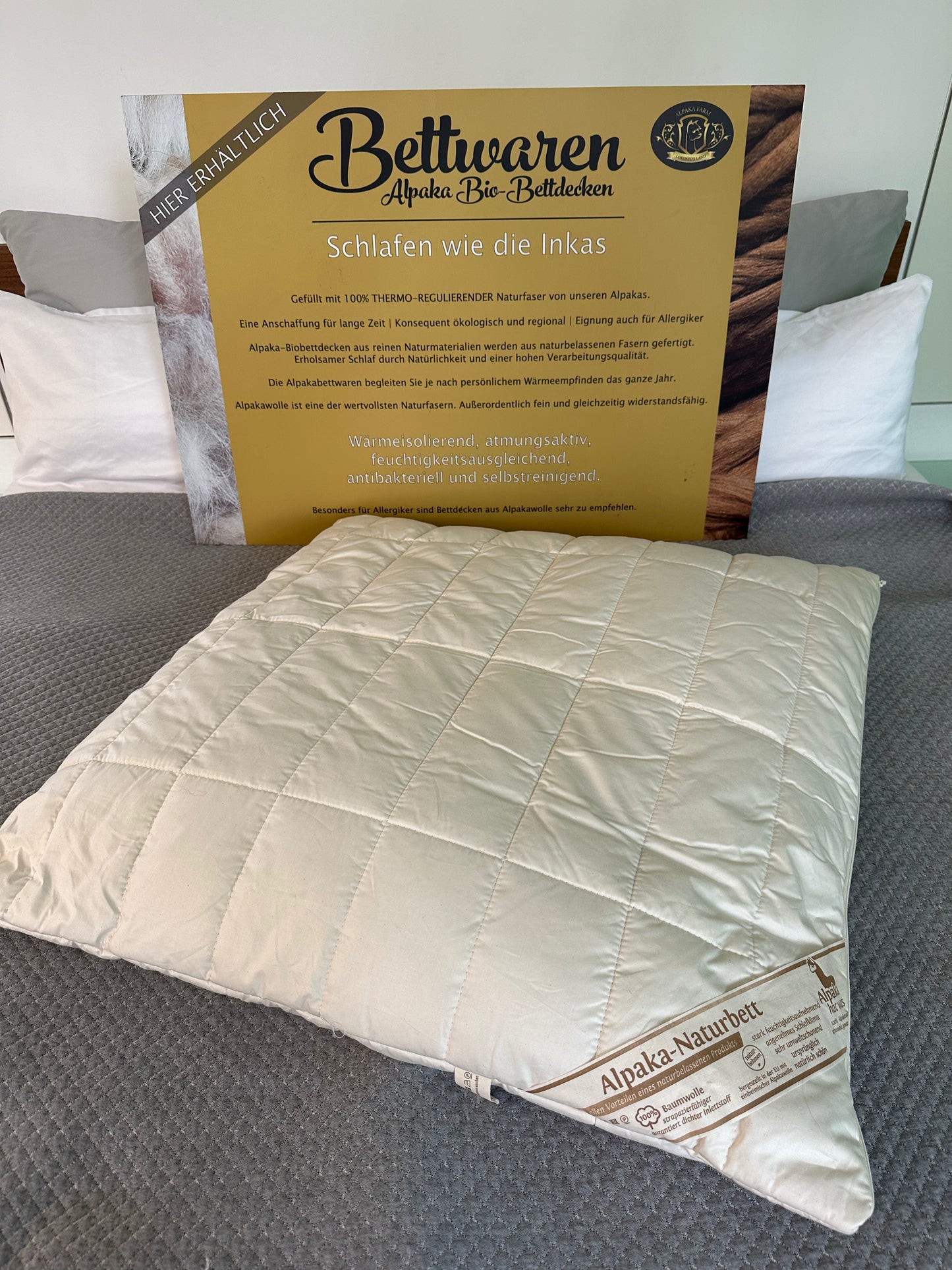 Weißes Alpaka Kissen auf grauer Decke